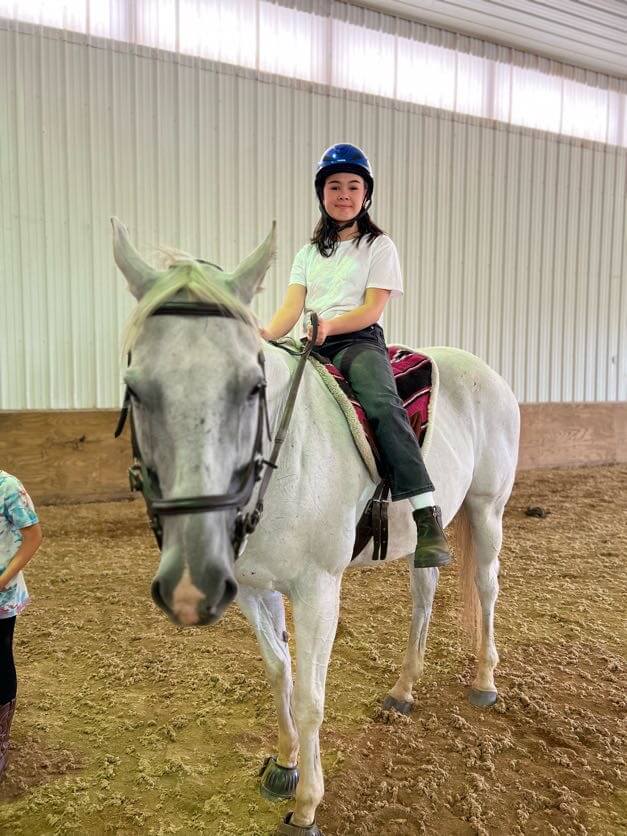 Summer camp kid riding bareback on horses.